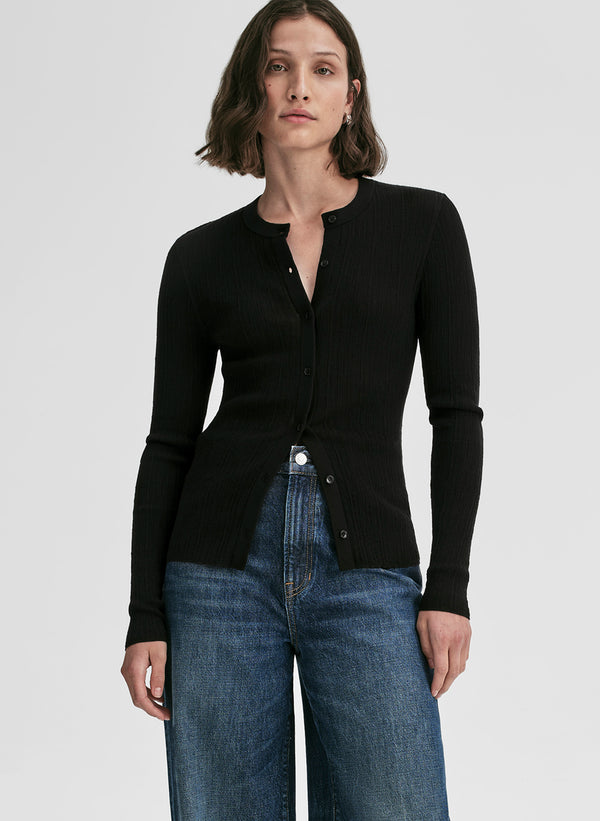 Woman wearing a black long-sleeve cardigan and blue jeans on a white background