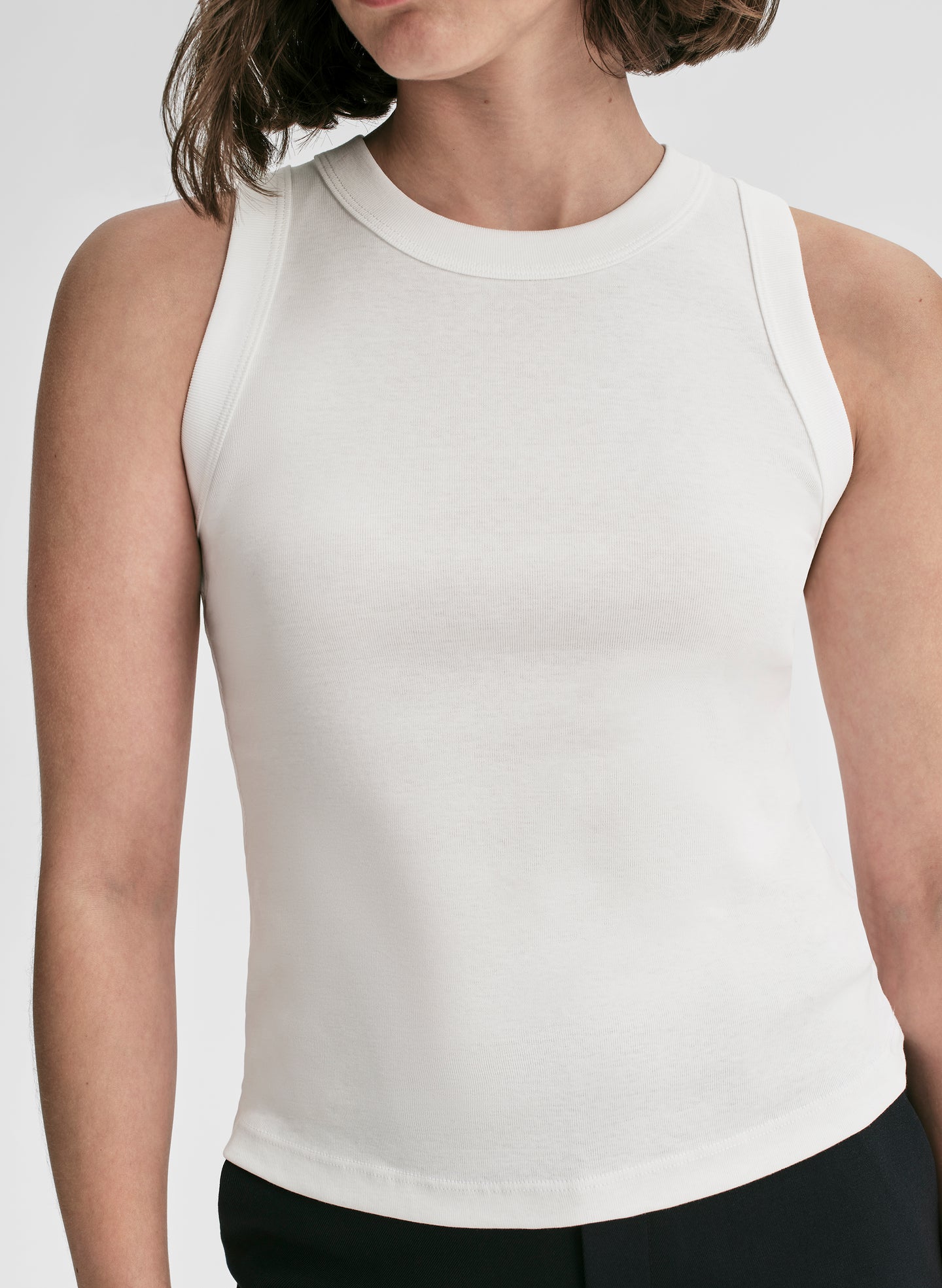 Person wearing a white sleeveless top on a plain background
