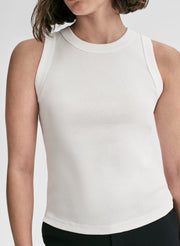Person wearing a white sleeveless top on a plain background
