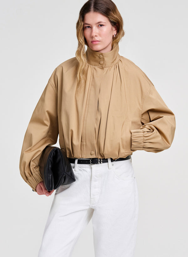 woman wearing light brown jacket and white denim jeans
