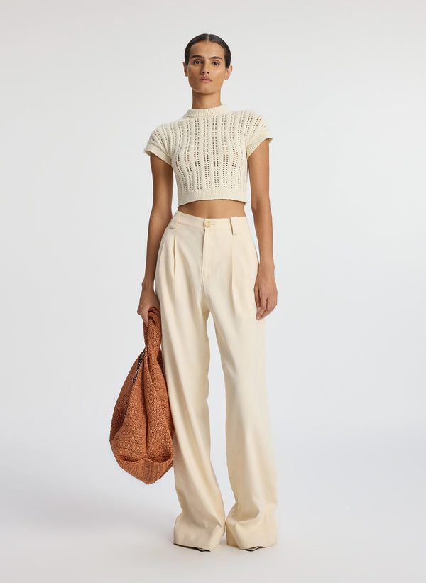 front view of woman wearing ivory short sleeve open weave top and beige wide leg pants