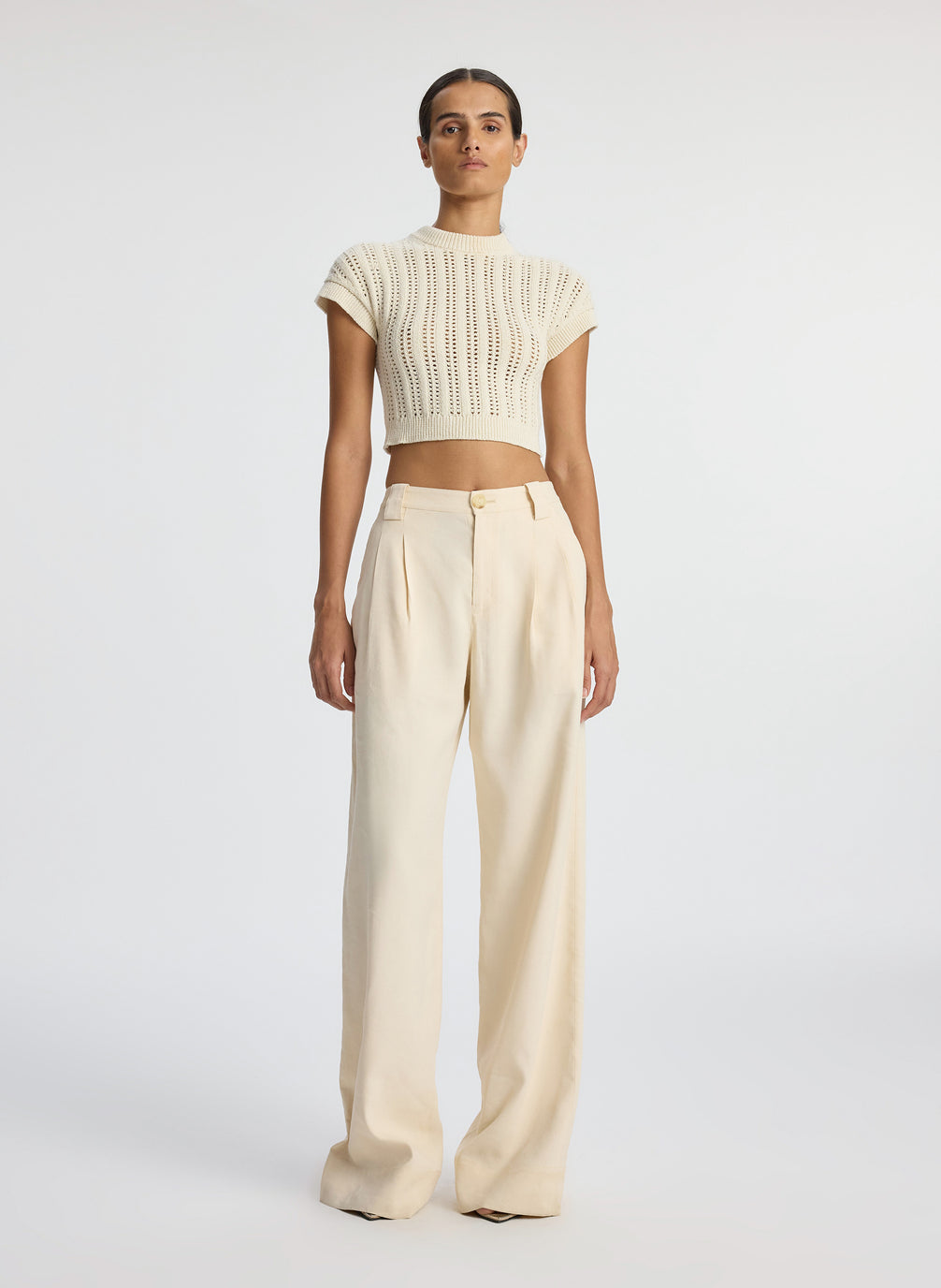 front view of woman wearing ivory short sleeve open weave top and beige wide leg pants