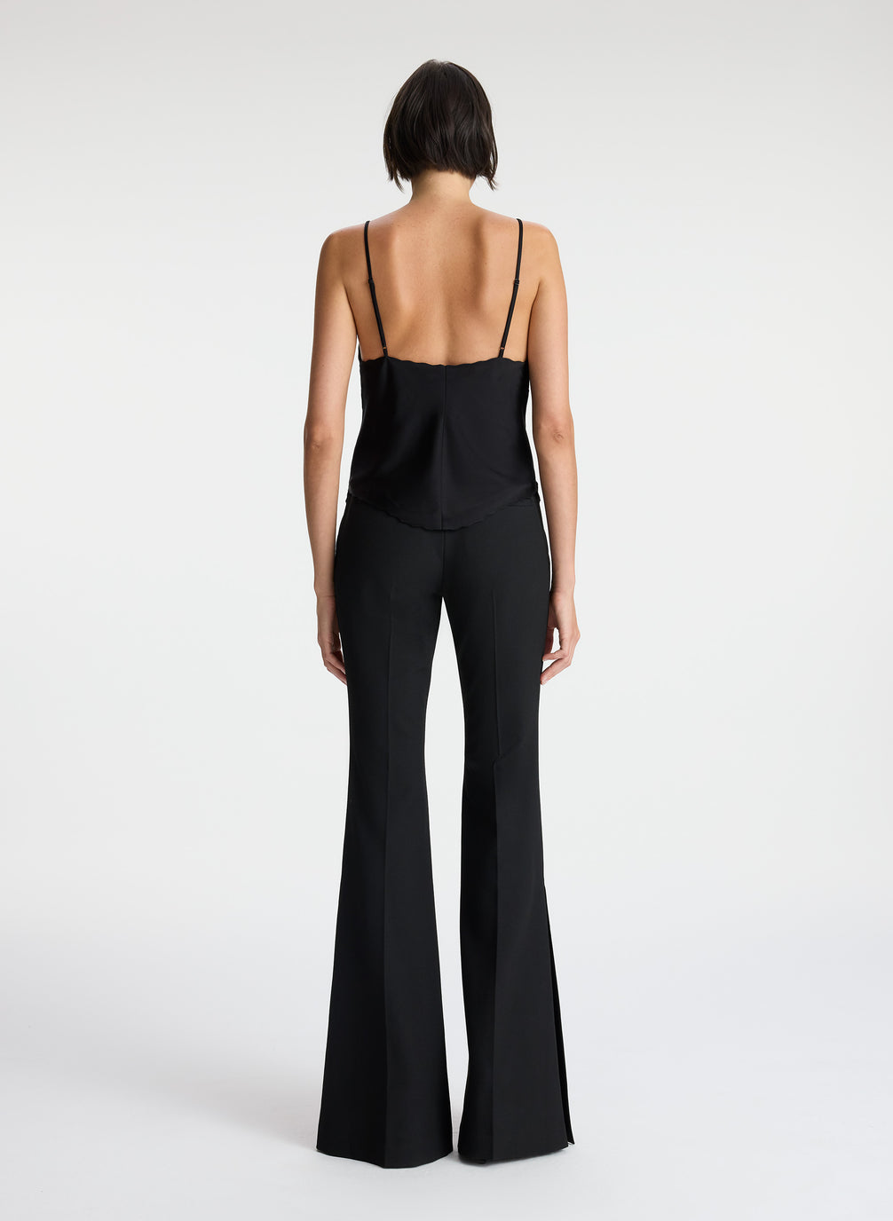 back view of woman wearing black camisole and black flared pants