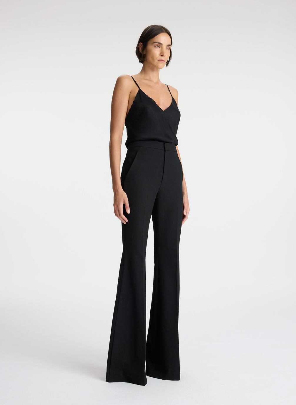 side view of woman wearing black camisole top and black flared pants