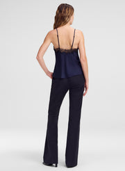 A woman shown from the back wearing a navy blue camisole top with black lace trim at the back and dark navy pants, photographed against a light gray studio background.