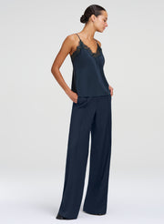 A woman modeling a green camisole top and matching pants with a lace-trimmed camisole top and wide-leg pants, photographed against a light gray studio background.