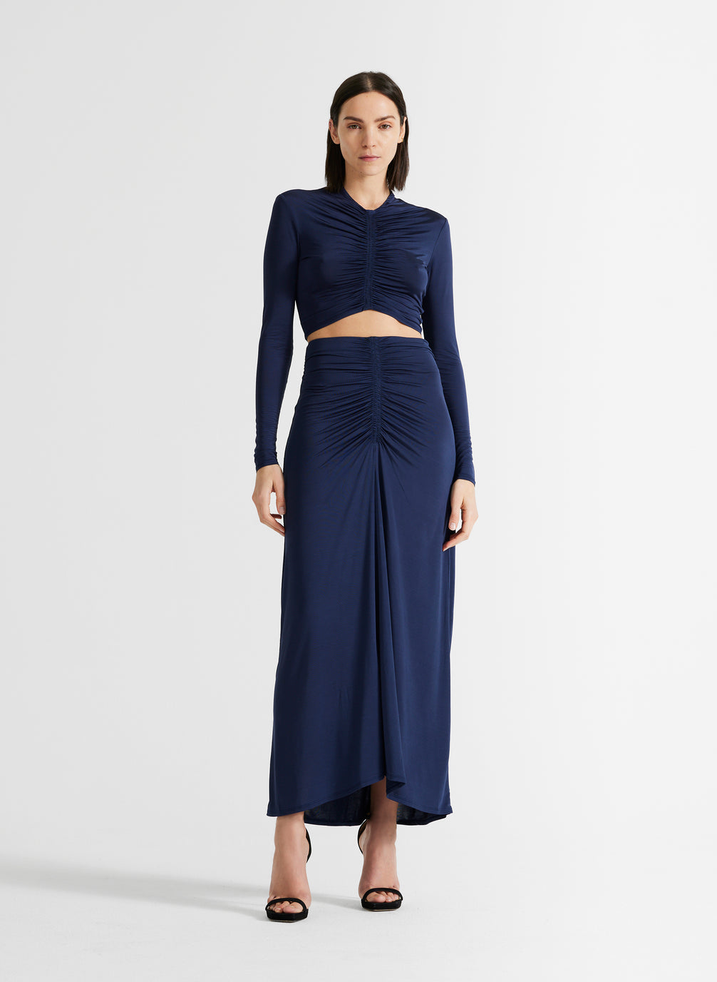 front view of woman in navy blue ruched crop top and matching navy blue maxi skirt