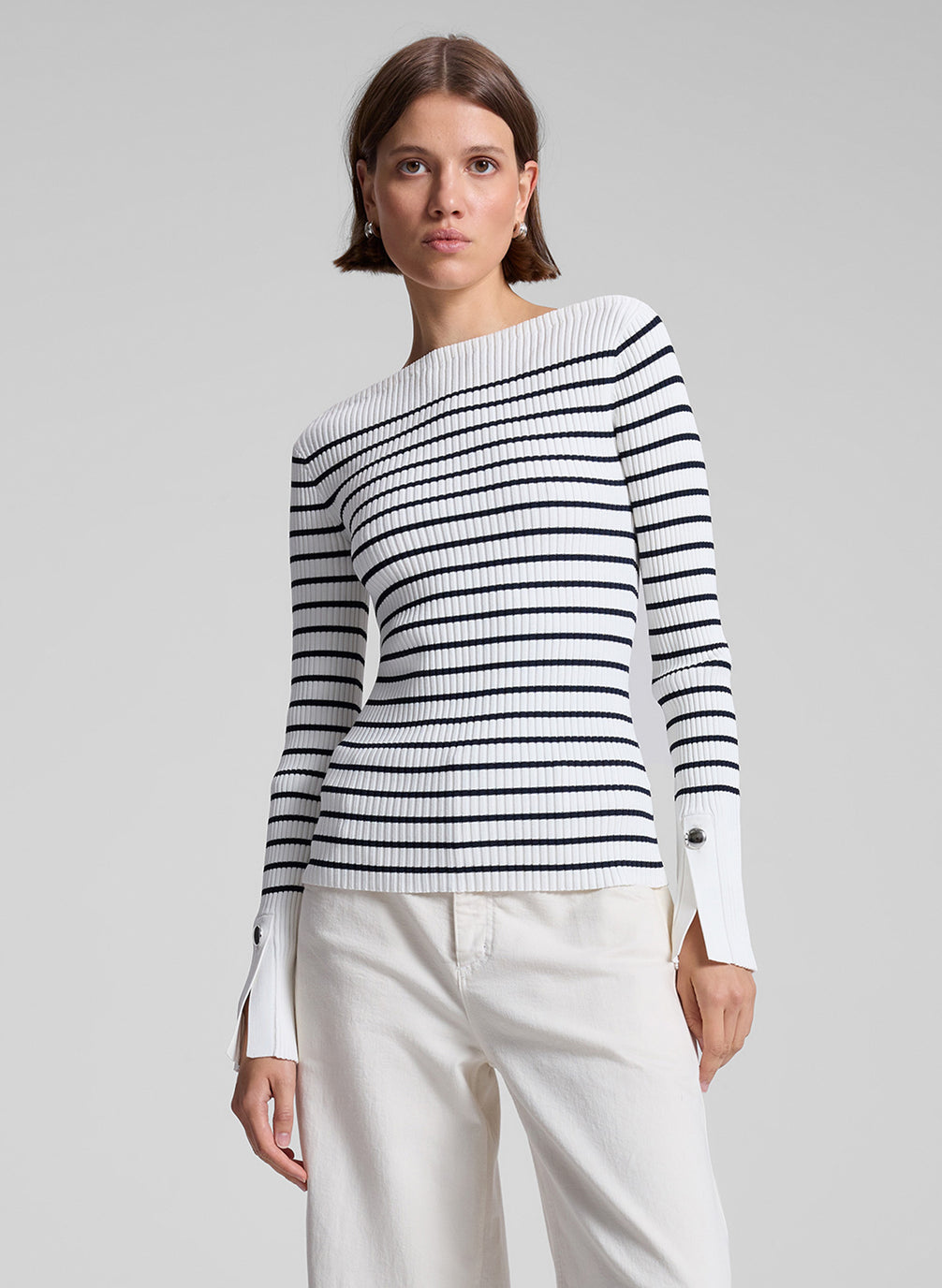 woman wearing long sleeve striped knit top and white denim pants