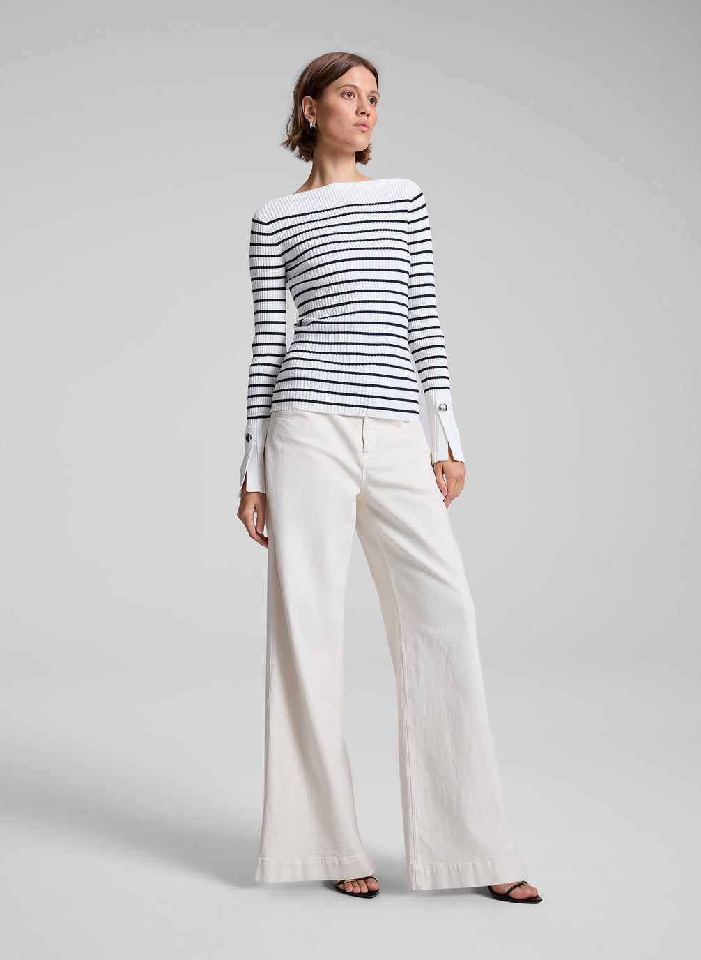 woman wearing long sleeve striped knit top and white denim pants