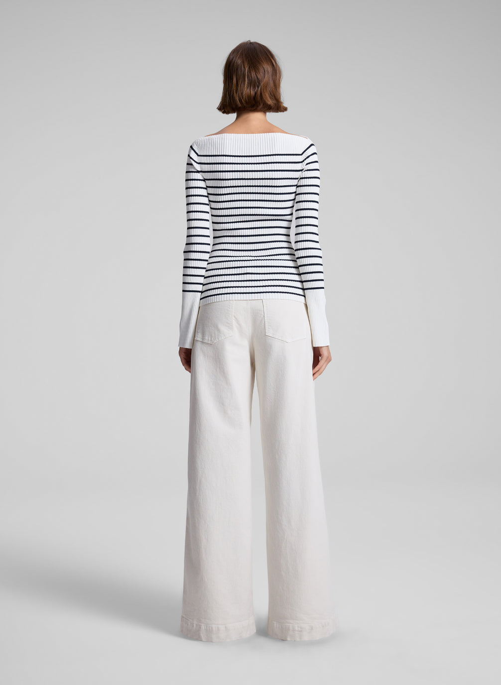 woman wearing long sleeve striped knit top and white denim pants