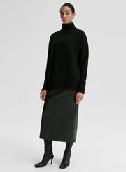 Woman wearing a black turtleneck sweater and black skirt on a white background