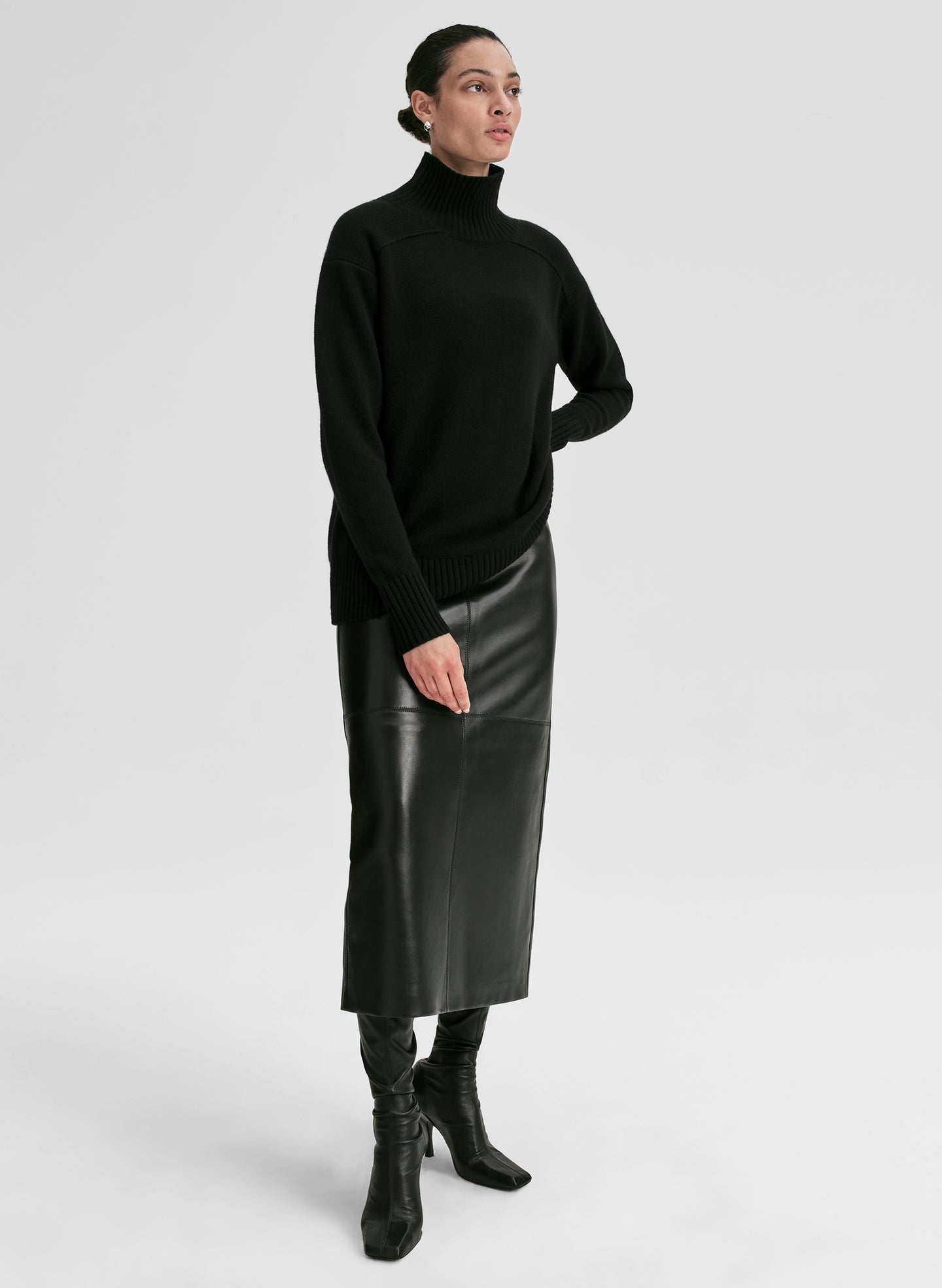 Person wearing a black turtleneck sweater and leather skirt on a white background