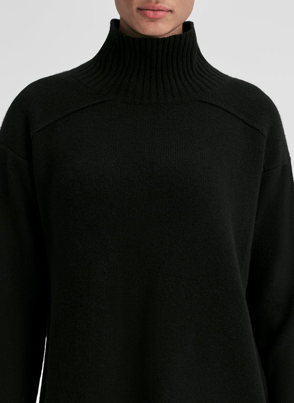 Black turtleneck sweater worn by a person on a light gray background