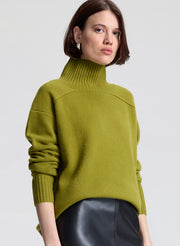 Woman wearing a green sweater and black leather skirt against a white background