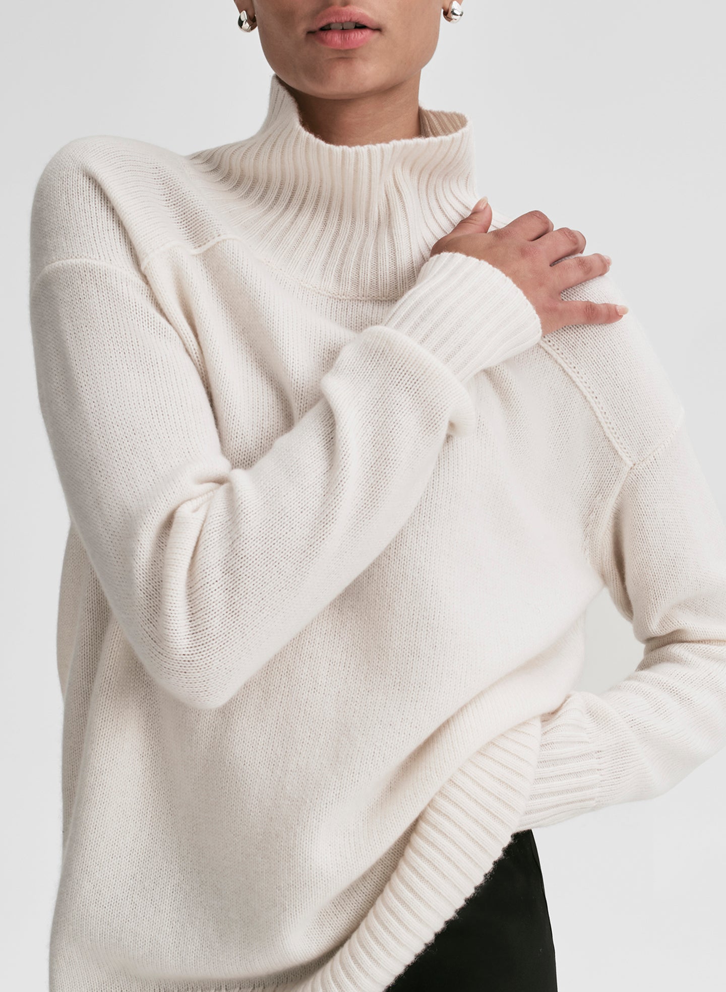 Person wearing a white turtleneck sweater on a plain background