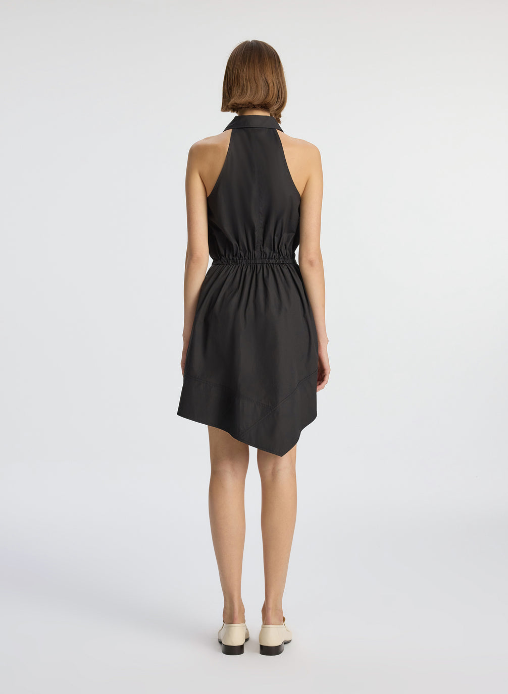 back view of woman wearing black sleeveless collared mini dress