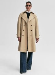 Person wearing a beige trench coat on a white background