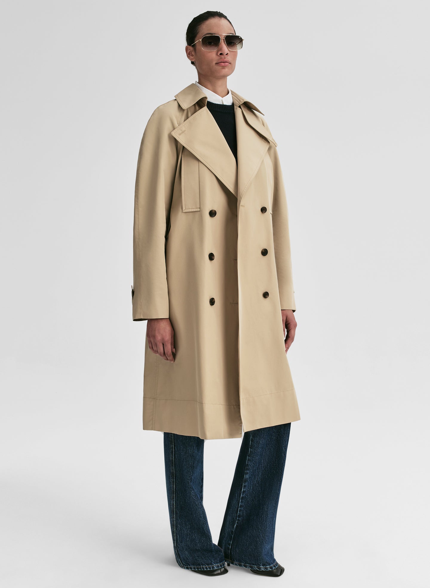 Person wearing a beige trench coat on a white background
