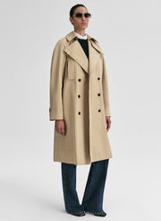 Person wearing a beige trench coat on a white background