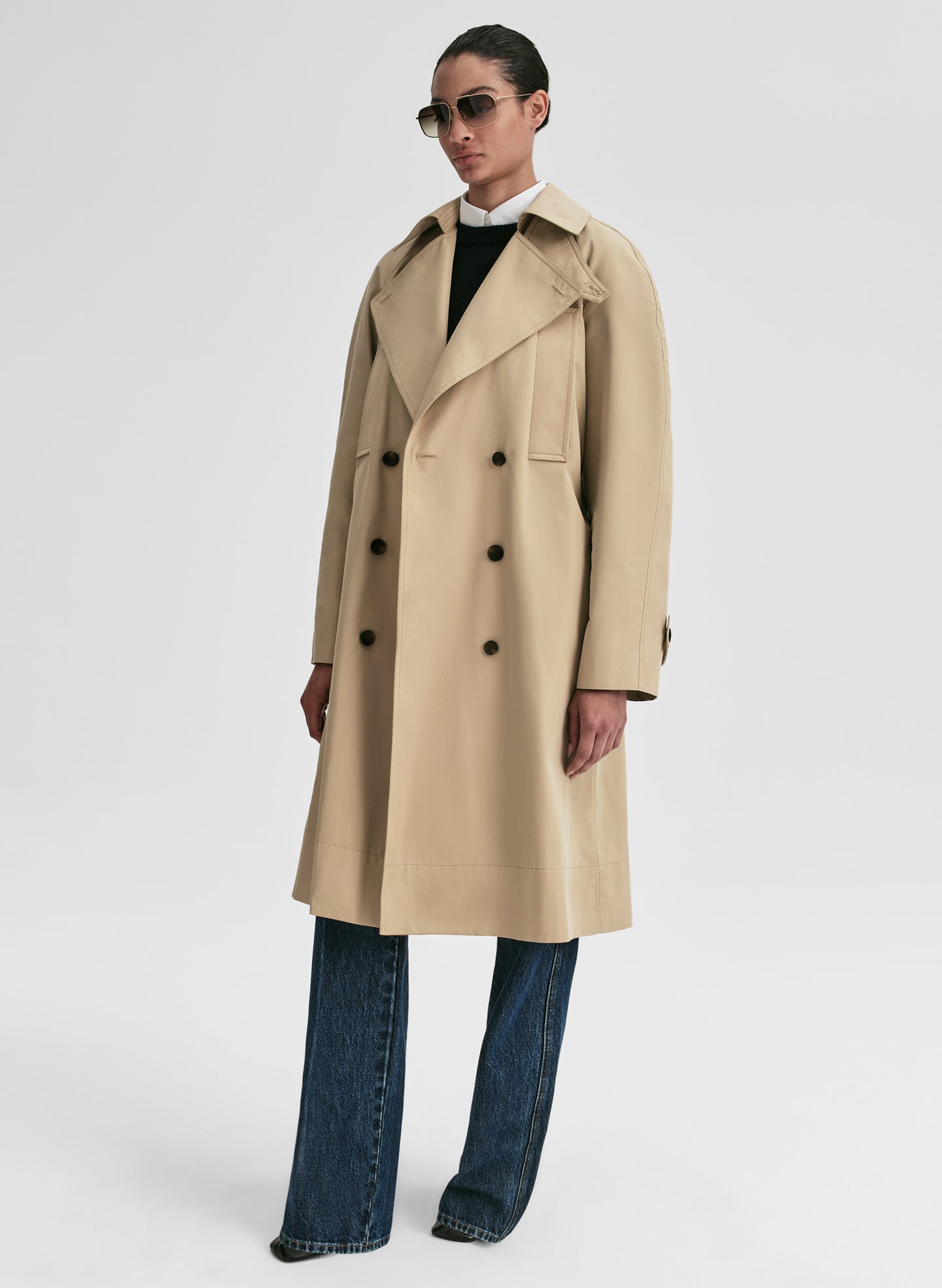 Person wearing a beige trench coat on a white background