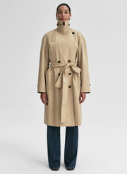 Person wearing a beige trench coat on a white background