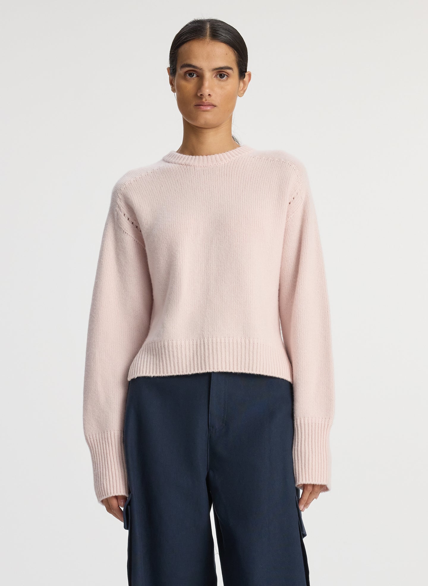 front view of woman wearing pink sweater and navy blue satin cargo pants