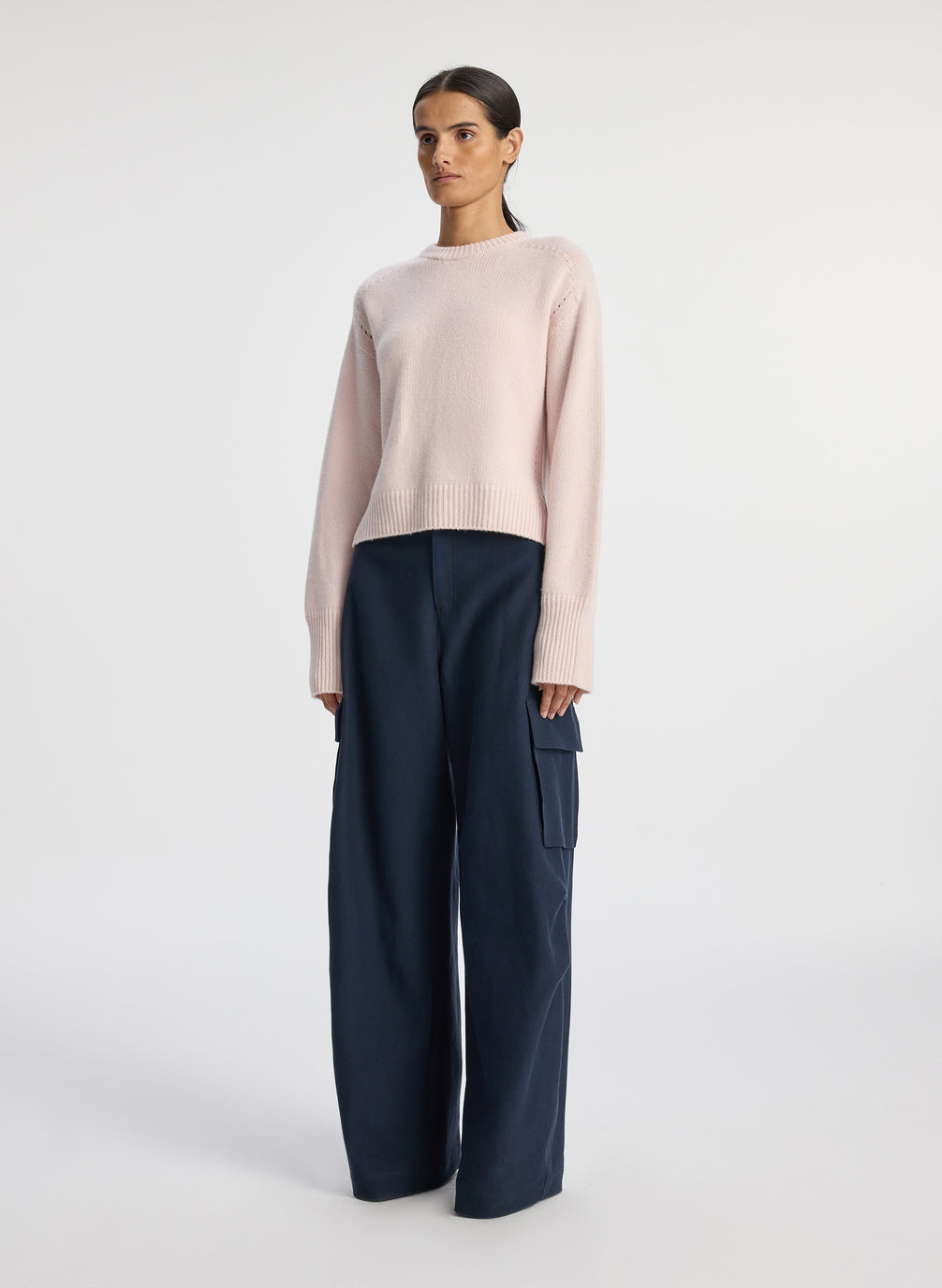 side view of woman wearing pink sweater and navy blue satin cargo pants