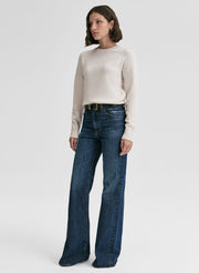 Woman wearing a white sweater and blue jeans on a white background