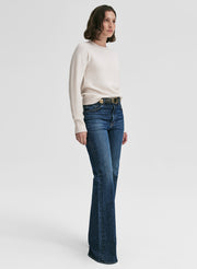 Woman wearing a white sweater and blue jeans on a white background