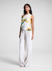 woman wearing one shoulder printed top and cream wide leg pants