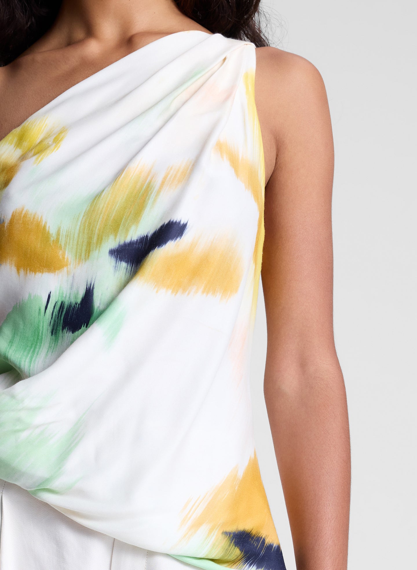 woman wearing one shoulder printed top and cream wide leg pants