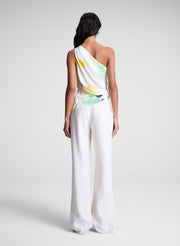 woman wearing one shoulder printed top and cream wide leg pants
