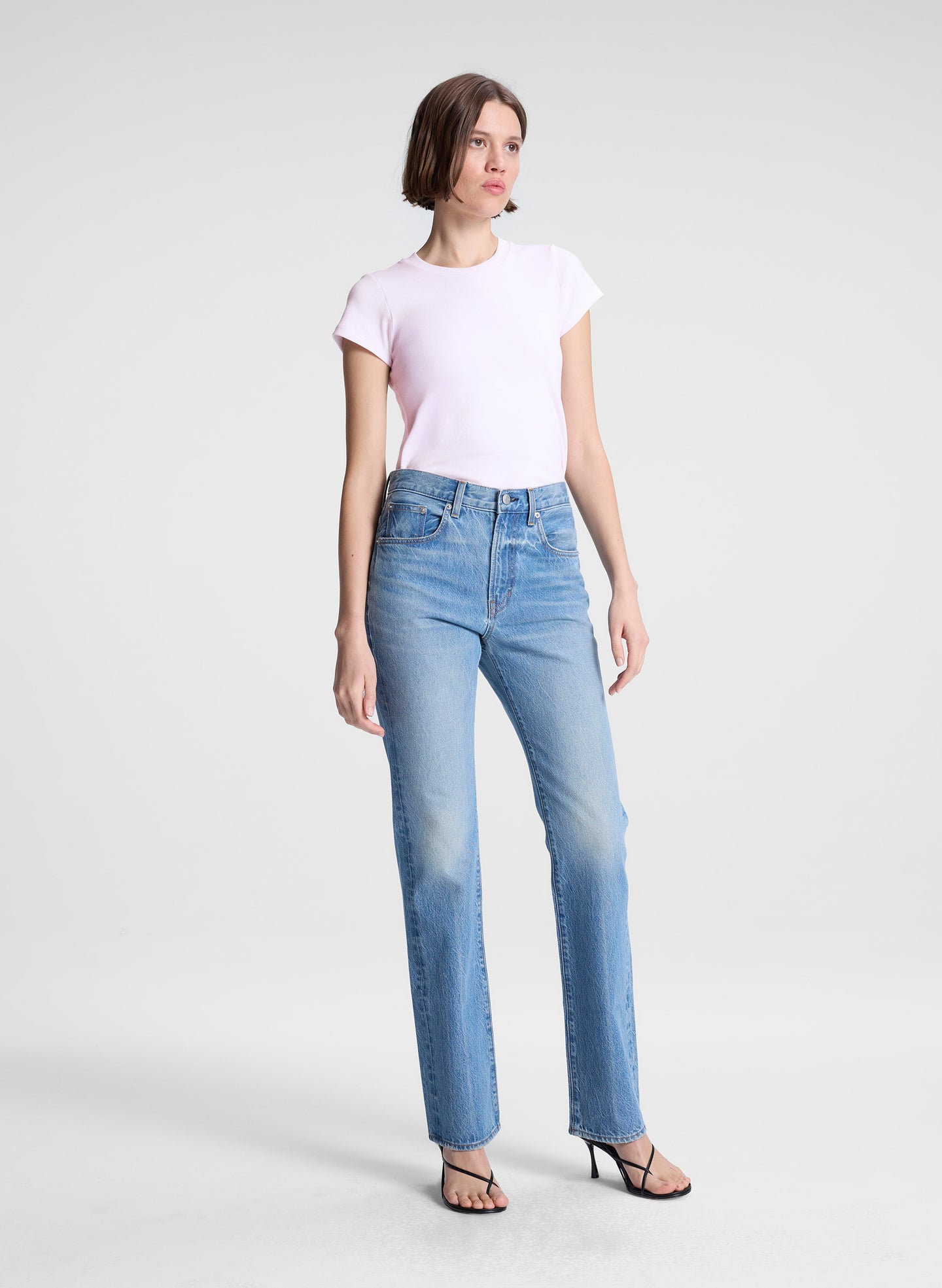 woman wearing light pink tee and light blue wash denim straight leg jeans