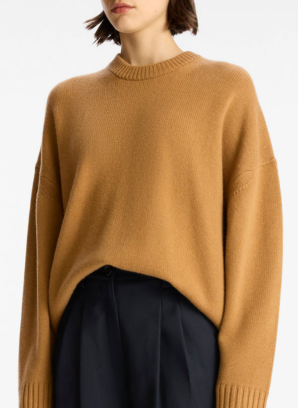 detail view of woman wearing tan cashmere long sleeve sweater
