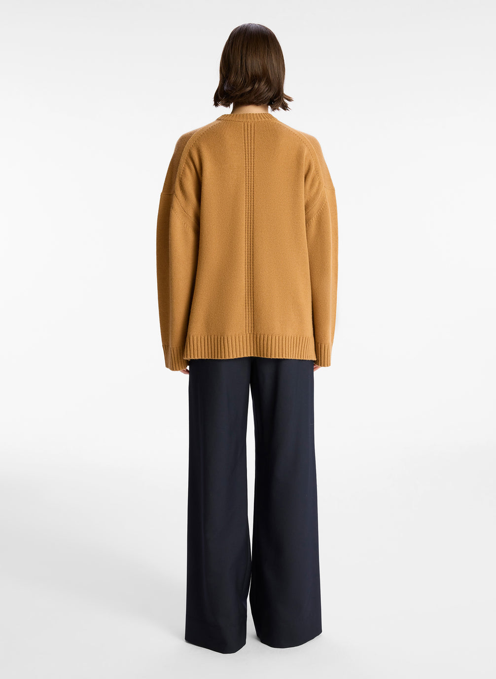 back view of woman wearing tan cashmere long sleeve sweater