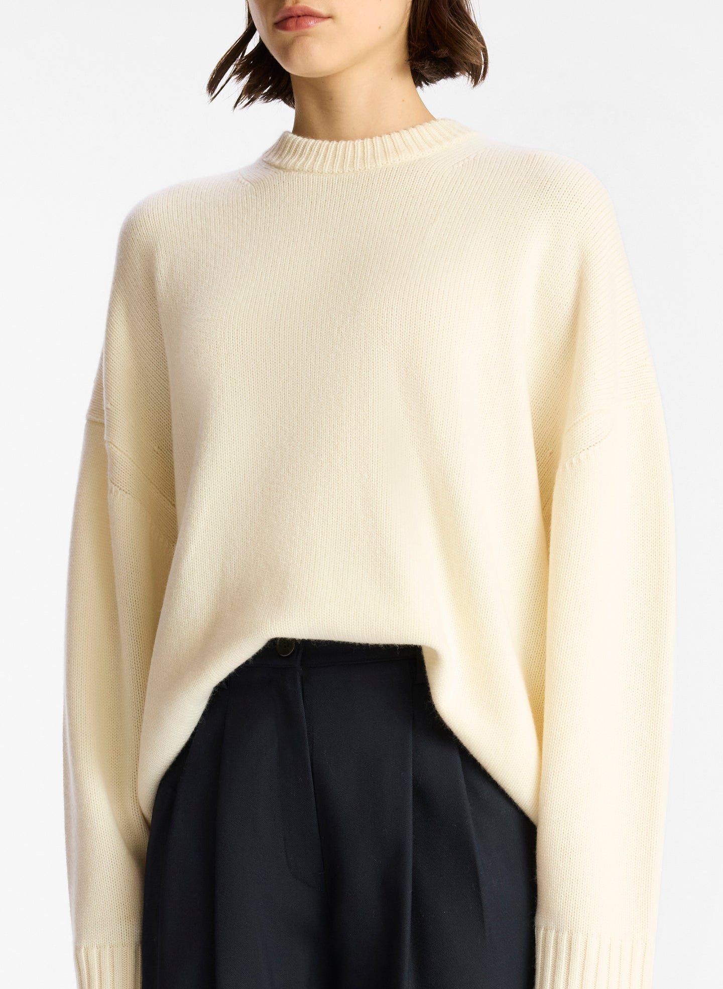 detail view of woman wearing off white cashmere long sleeve sweater