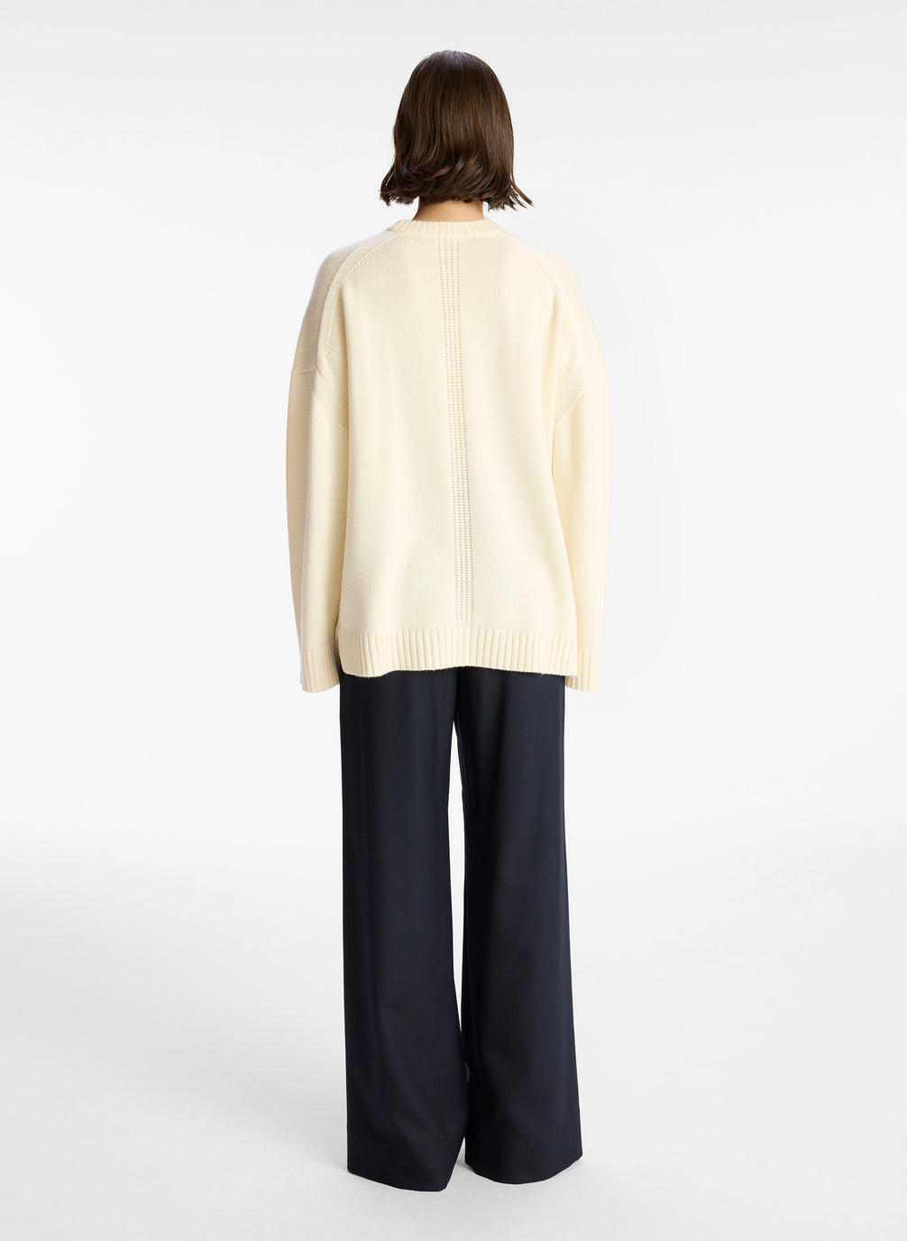 back view of woman wearing off white cashmere long sleeve sweater