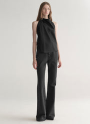 Woman wearing a black sleeveless top and black denim jeans on a plain background