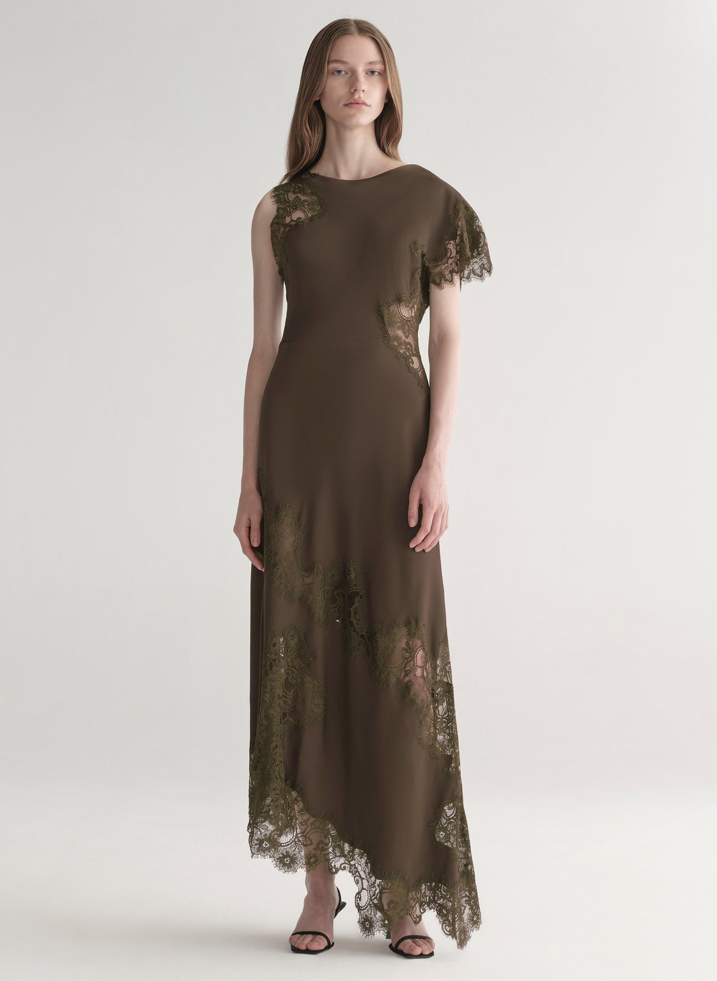 Woman wearing an olive green evening gown with lace details on a white background