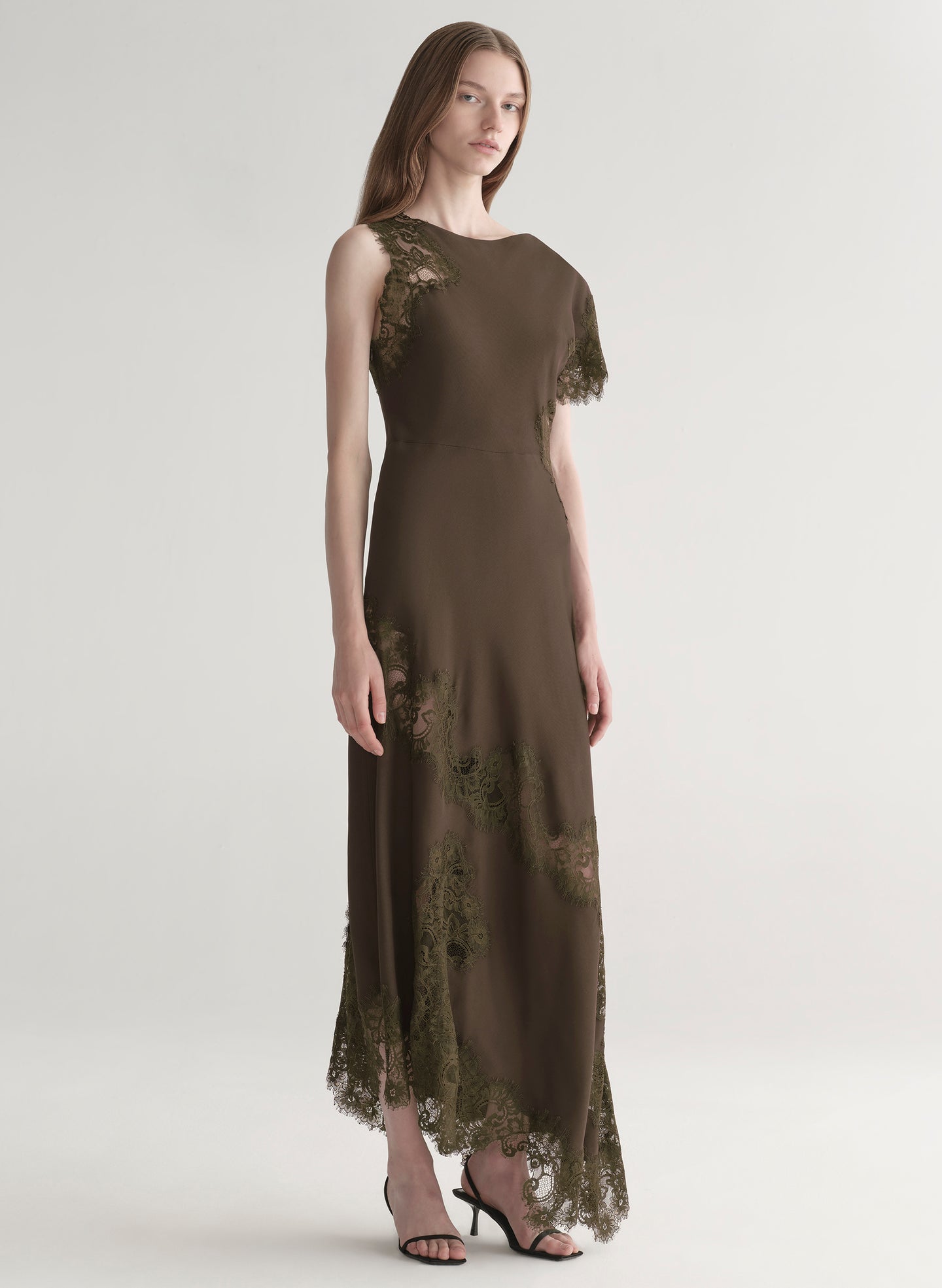 Woman wearing an olive green evening gown with lace details on a white background