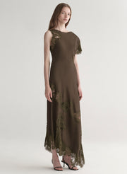 Woman wearing an olive green evening gown with lace details on a white background