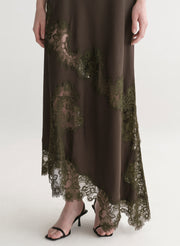 Woman wearing an olive green evening gown with lace details on a white background