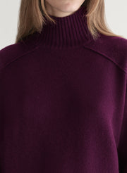 Woman wearing a purple sweater against a plain background