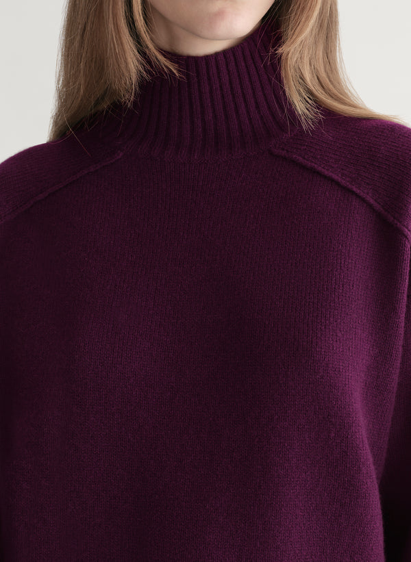 Woman wearing a purple sweater against a plain background