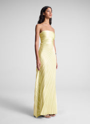 Woman wearing a strapless yellow gown on a plain background