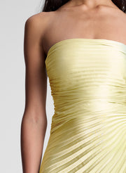 Light yellow strapless dress on a plain background