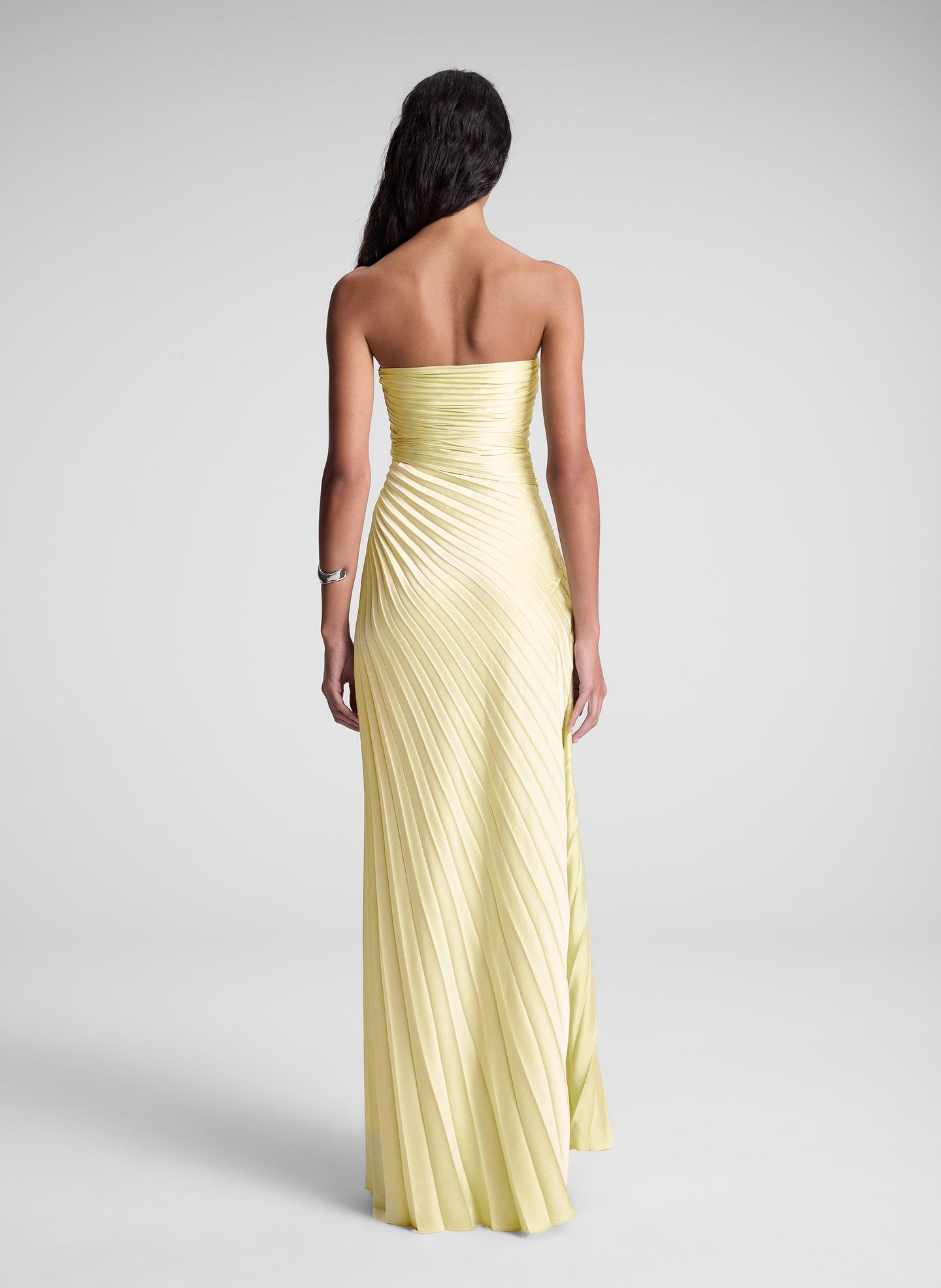 Woman wearing a strapless yellow evening gown on a plain background