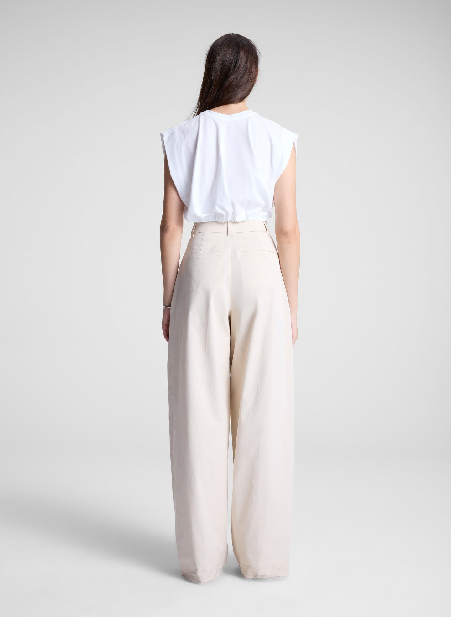 woman wearing white cropped tee and beige pants