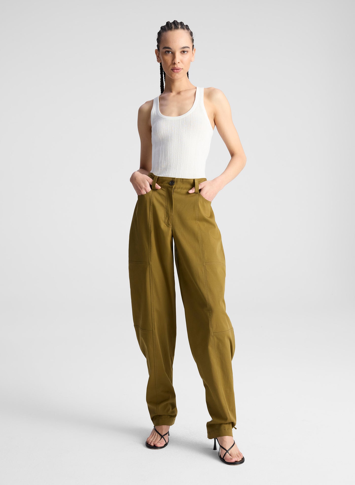 woman wearing white fine gauge voile knit tank top and green pants with tie tapering detail