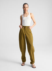 woman wearing white fine gauge voile knit tank top and green pants with tie tapering detail